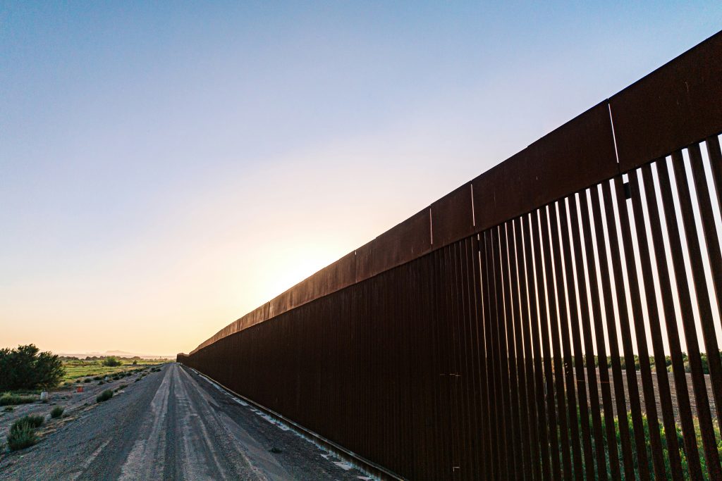 a long metal fence on a dirt road
