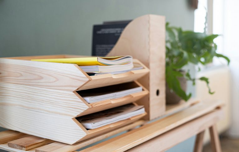 a wooden desk with a file drawer and a plant