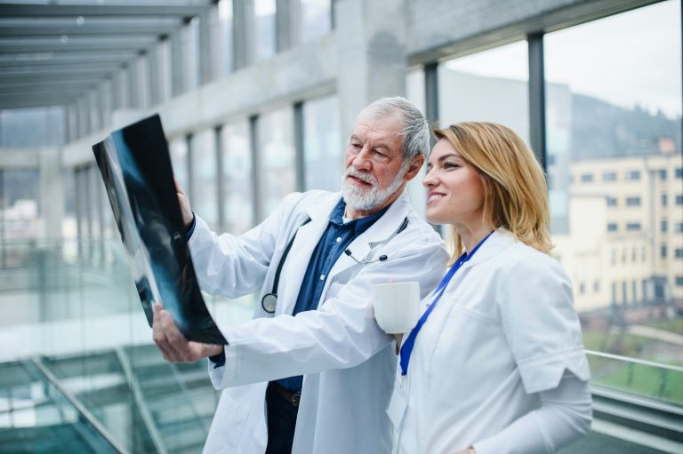 a man and woman in white lab coats looking at an x-ray