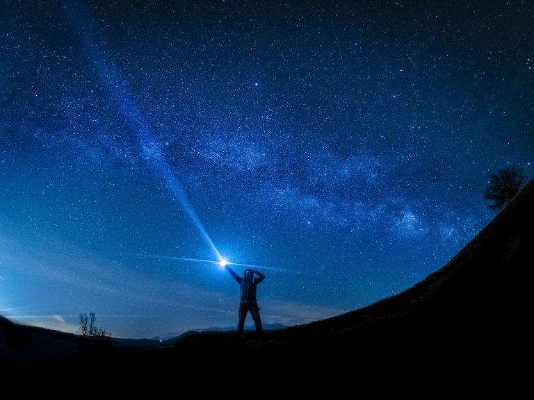 a person holding a flashlight in the sky