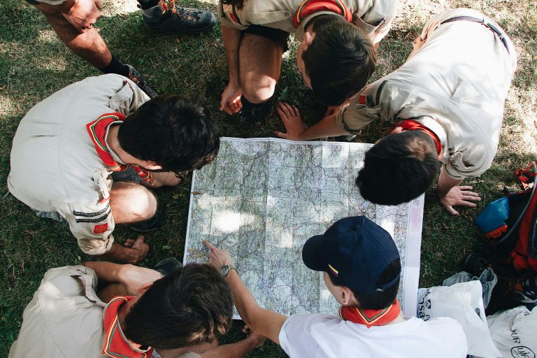 a group of boys in uniform looking at a map
