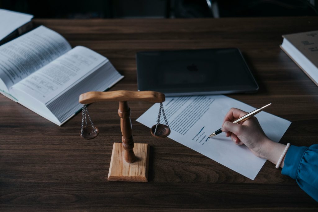 a hand signing a document on a wooden table
