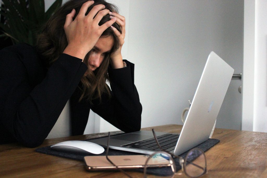a woman holding her head in front of a laptop