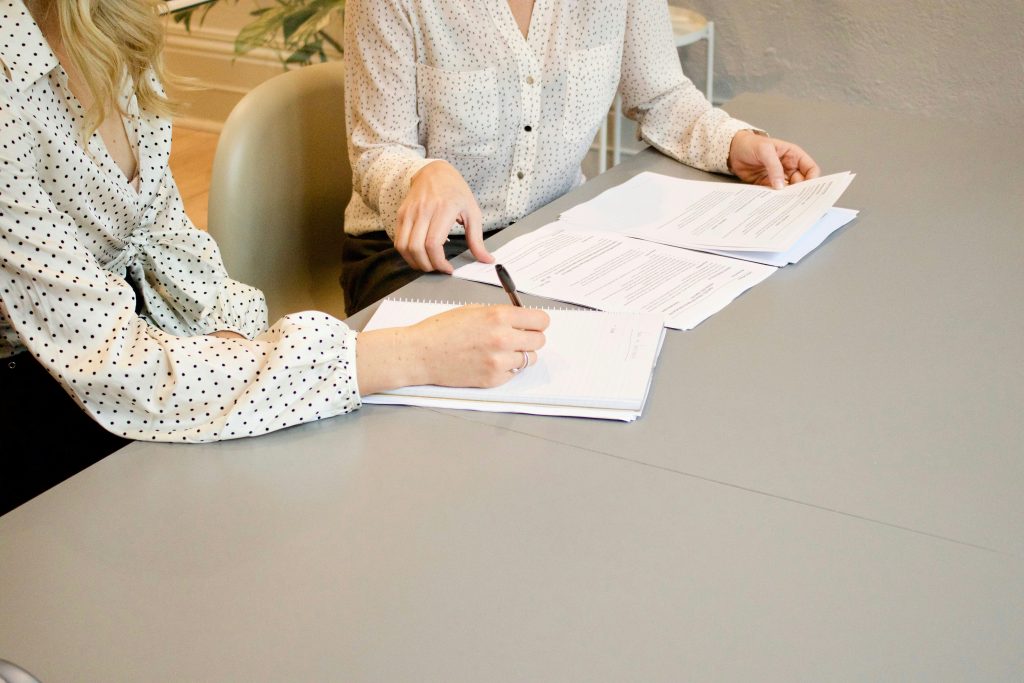 a woman sitting at a table with papers and a pen