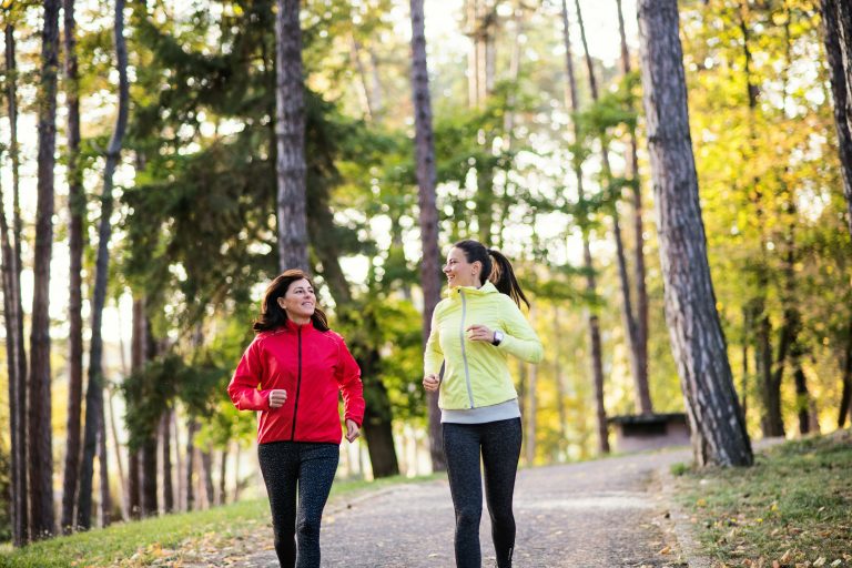 two women running on a path in the woods