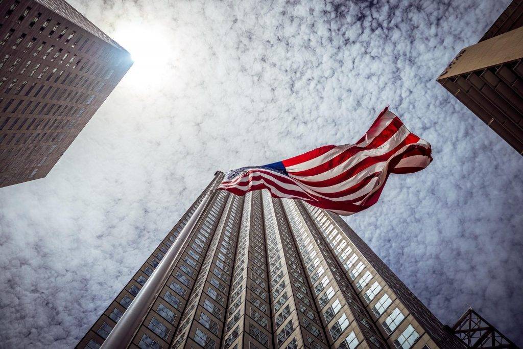 USA flag fluttering against backdrop of city skyscrapers.
