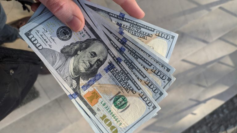 a hand holding a fan of paper money